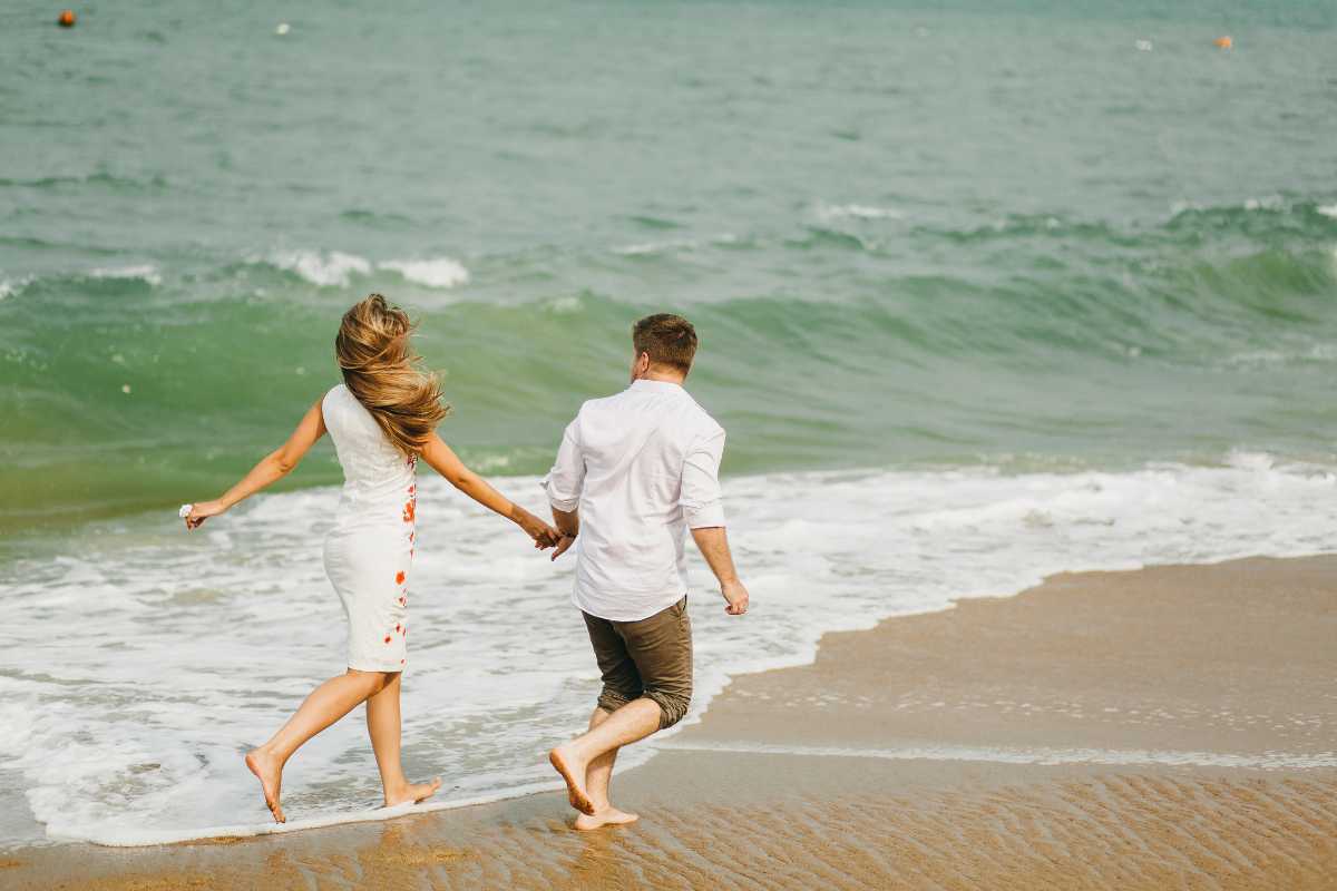 Spiaggia di Vieste con bambini che giocano sulla sabbia, ombrelloni colorati, mare calmo e fondale basso, atmosfera rilassata e familiare